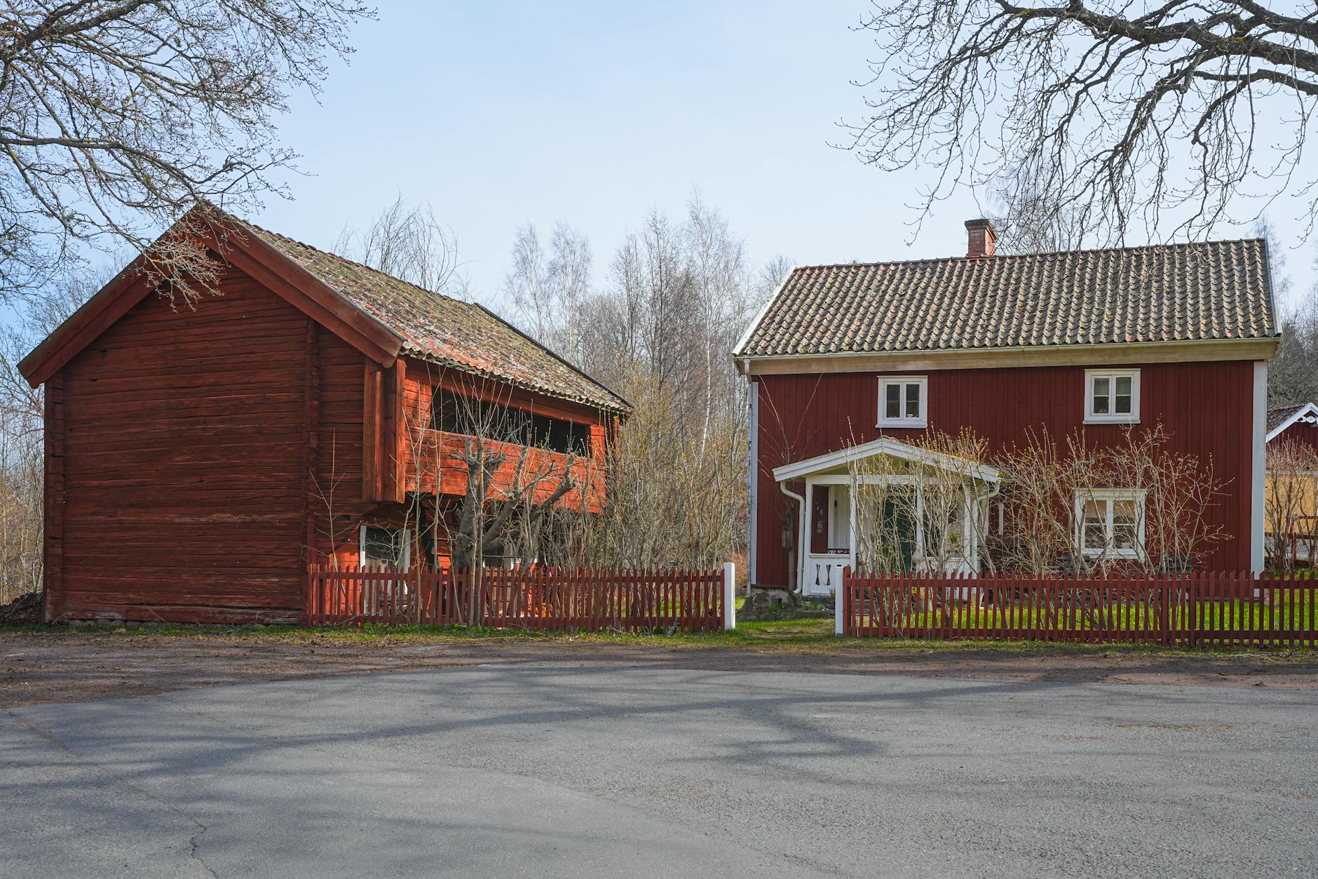 Czerwony drewniany dom skandynawski wśród drzew wczesną wiosną