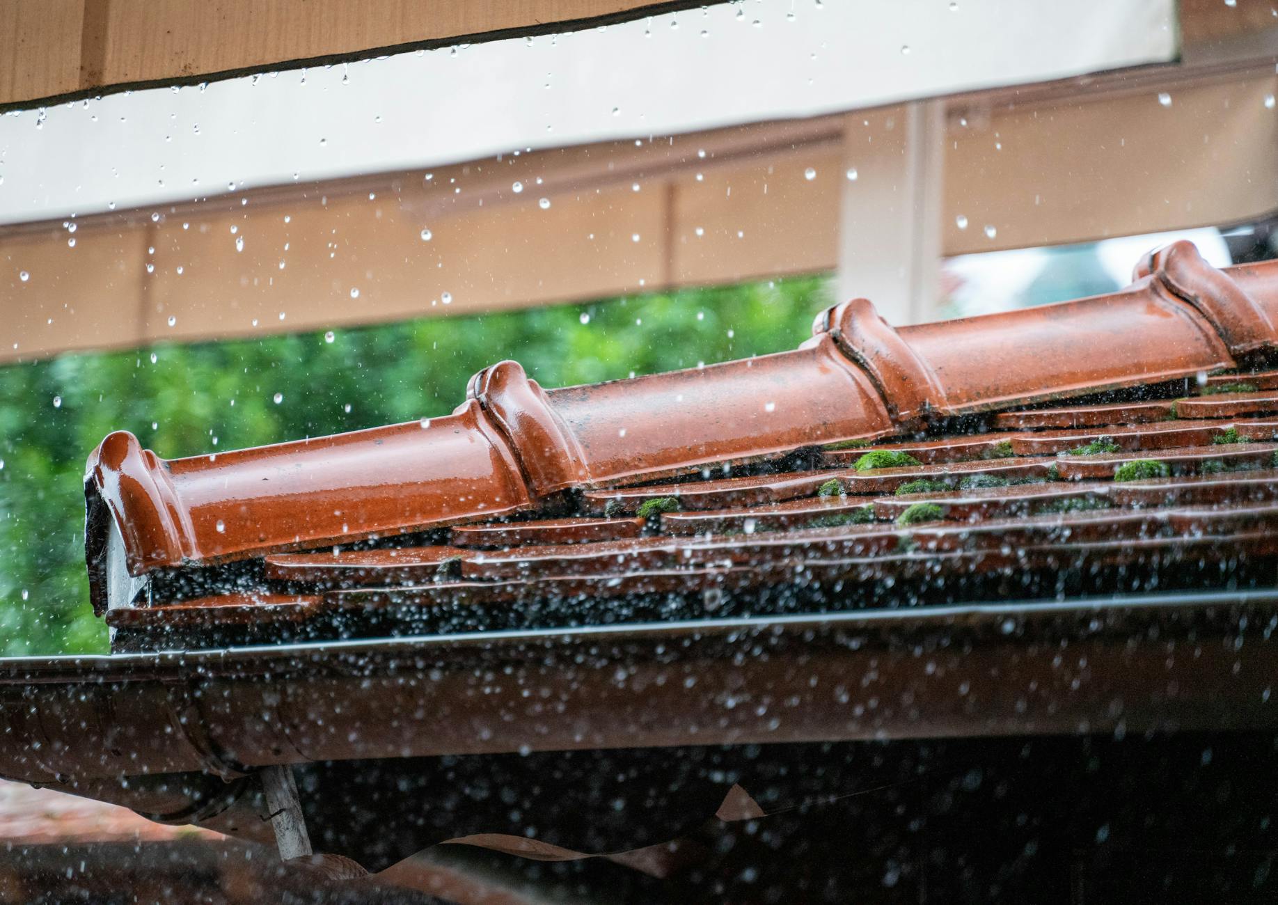 Krople deszczu spływające z krawędzi dachówek podczas ulewy