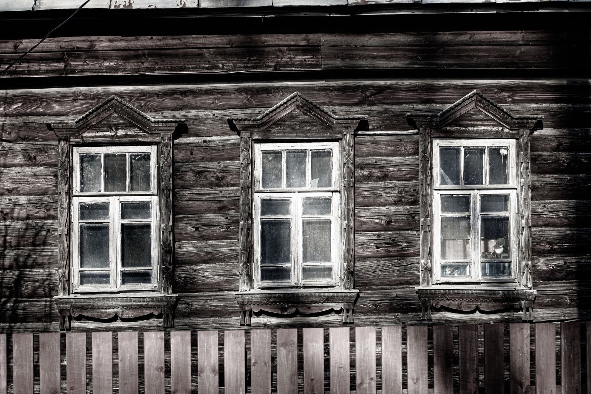 Stara drewniana elewacja domu z podniszczonymi oknami vintage