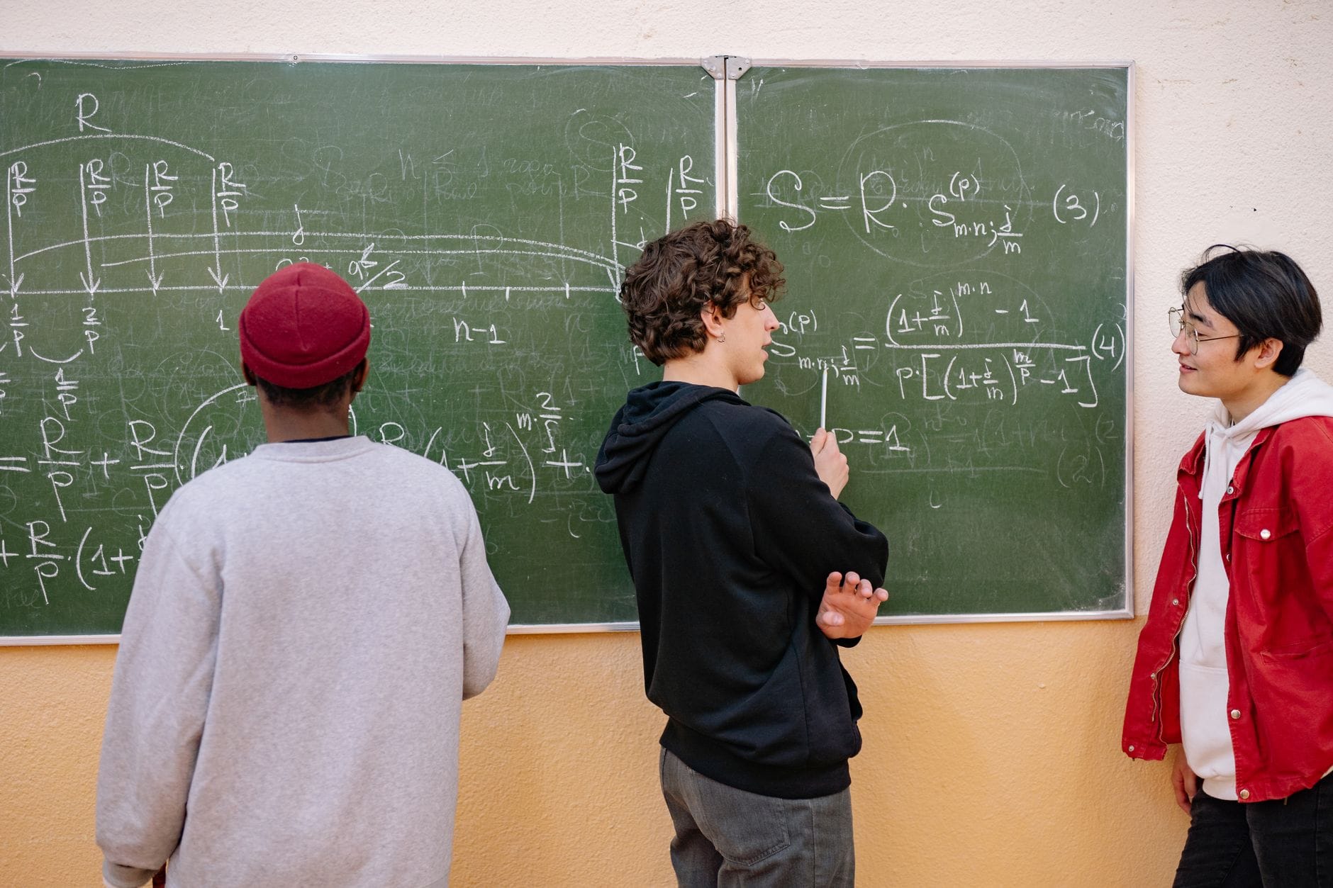Uczniowie omawiają równania matematyczne przy tablicy w klasie