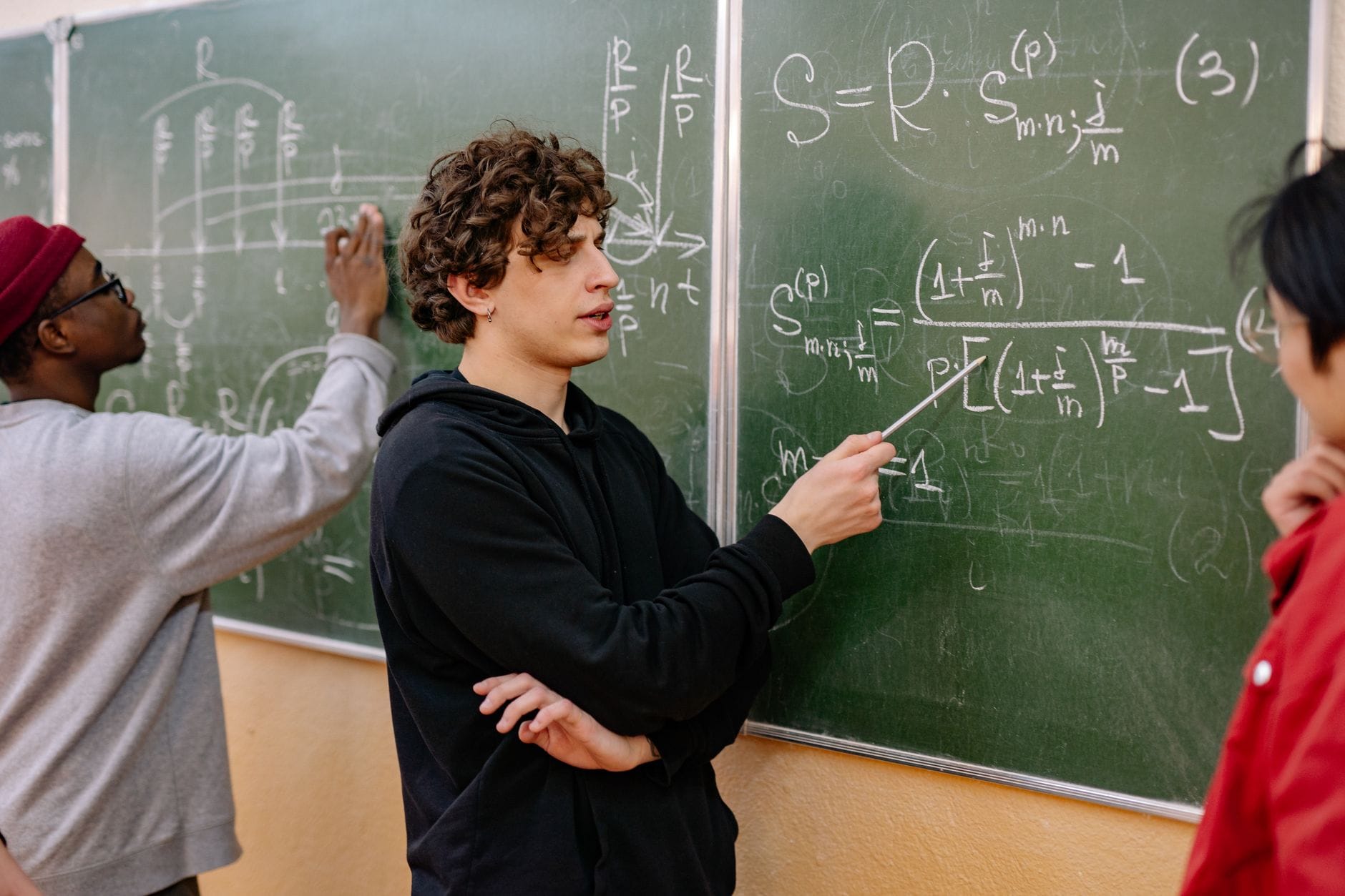 Uczniowie przy tablicy analizują złożone równania matematyczne